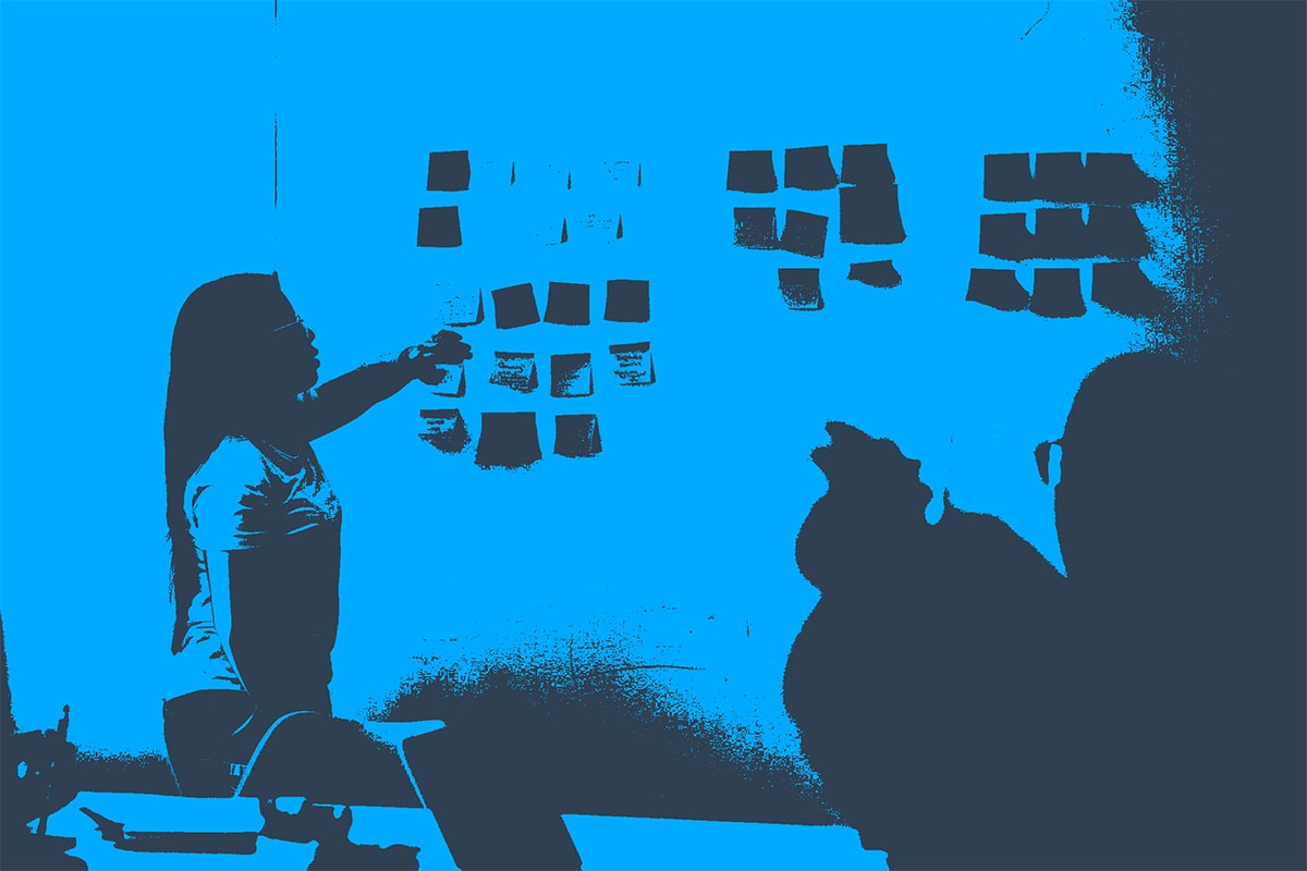 woman placing sticky note post-its on board design thinking practice